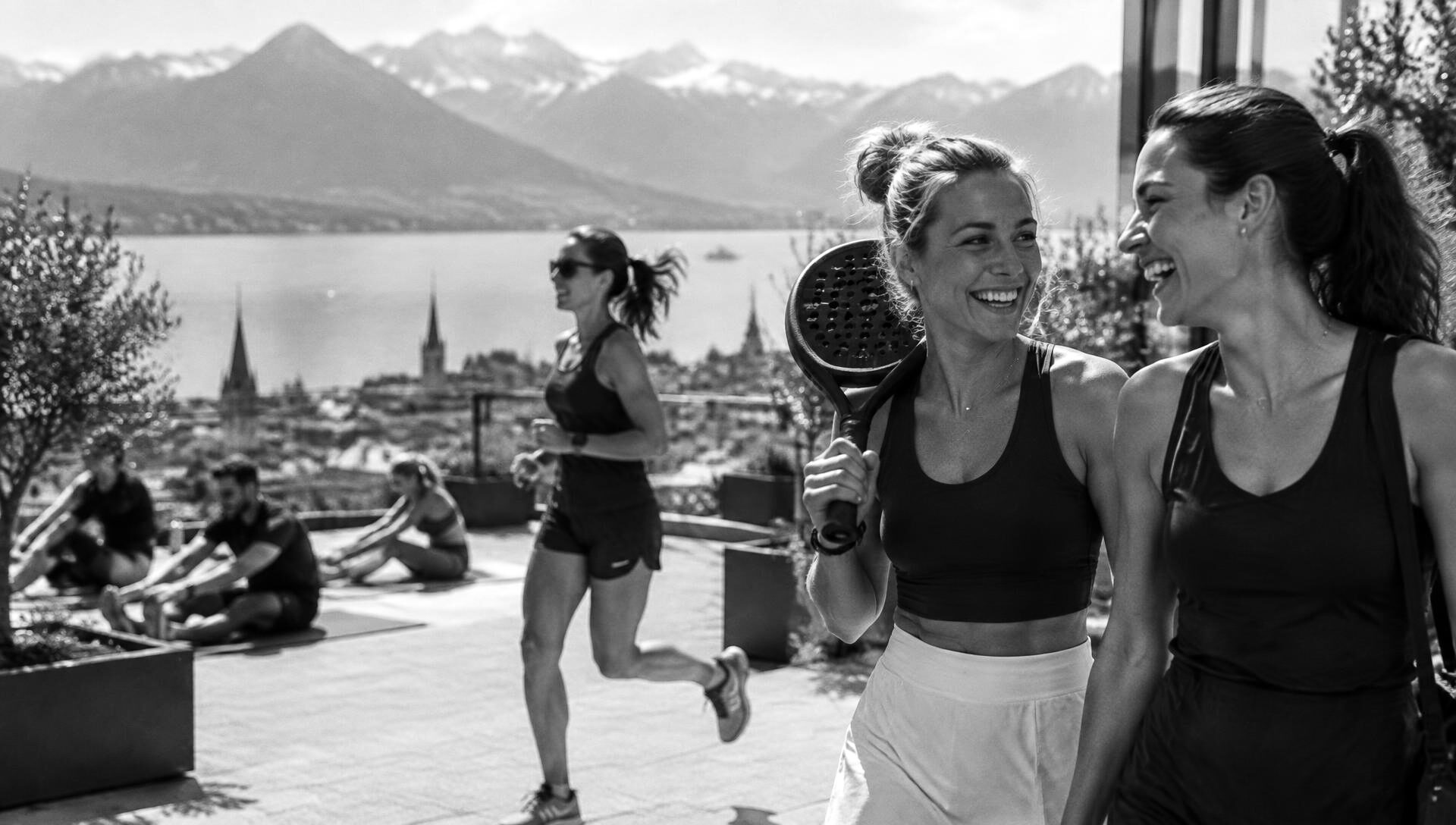 Friends together after padel, a woman running past and a group stretching on a terrace above a Swiss lake